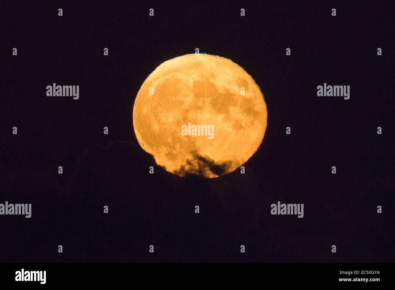 Highcliffe, Dorset, Royaume-Uni. 5 juillet 2020. Météo Royaume-Uni. La pleine Buck Moon brille orange alors qu'elle émerge de derrière une banque de nuages, vue de Highcliffe dans Dorset peu après la lune. Crédit photo : Graham Hunt/Alay Live News Banque D'Images