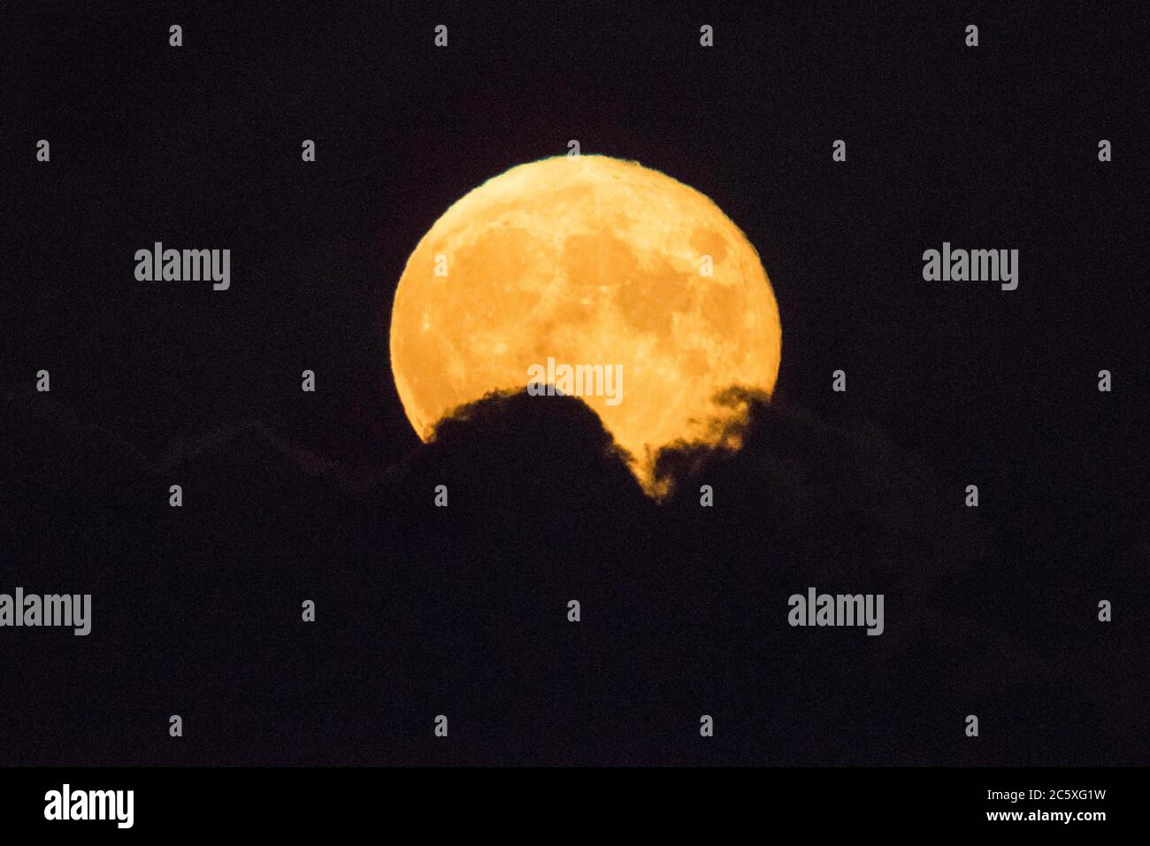 Highcliffe, Dorset, Royaume-Uni. 5 juillet 2020. Météo Royaume-Uni. La pleine Buck Moon brille orange alors qu'elle émerge de derrière une banque de nuages, vue de Highcliffe dans Dorset peu après la lune. Crédit photo : Graham Hunt/Alay Live News Banque D'Images