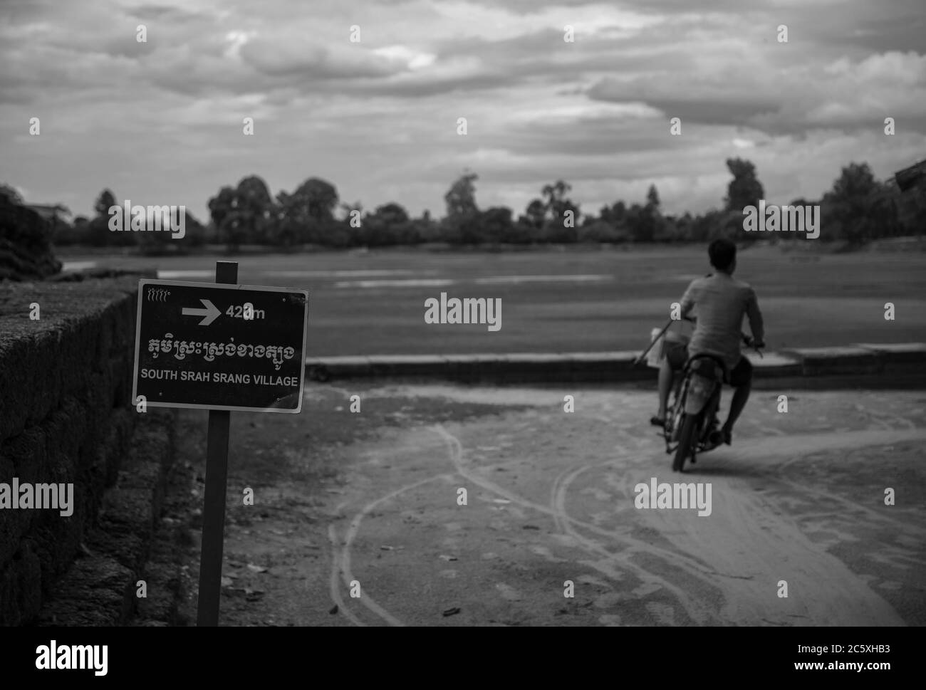 Un jeune homme conduit sa moto sur un chemin vers le village sud de Srah Srang - Angkor Wat, Siem Reap, Cambodge. Banque D'Images