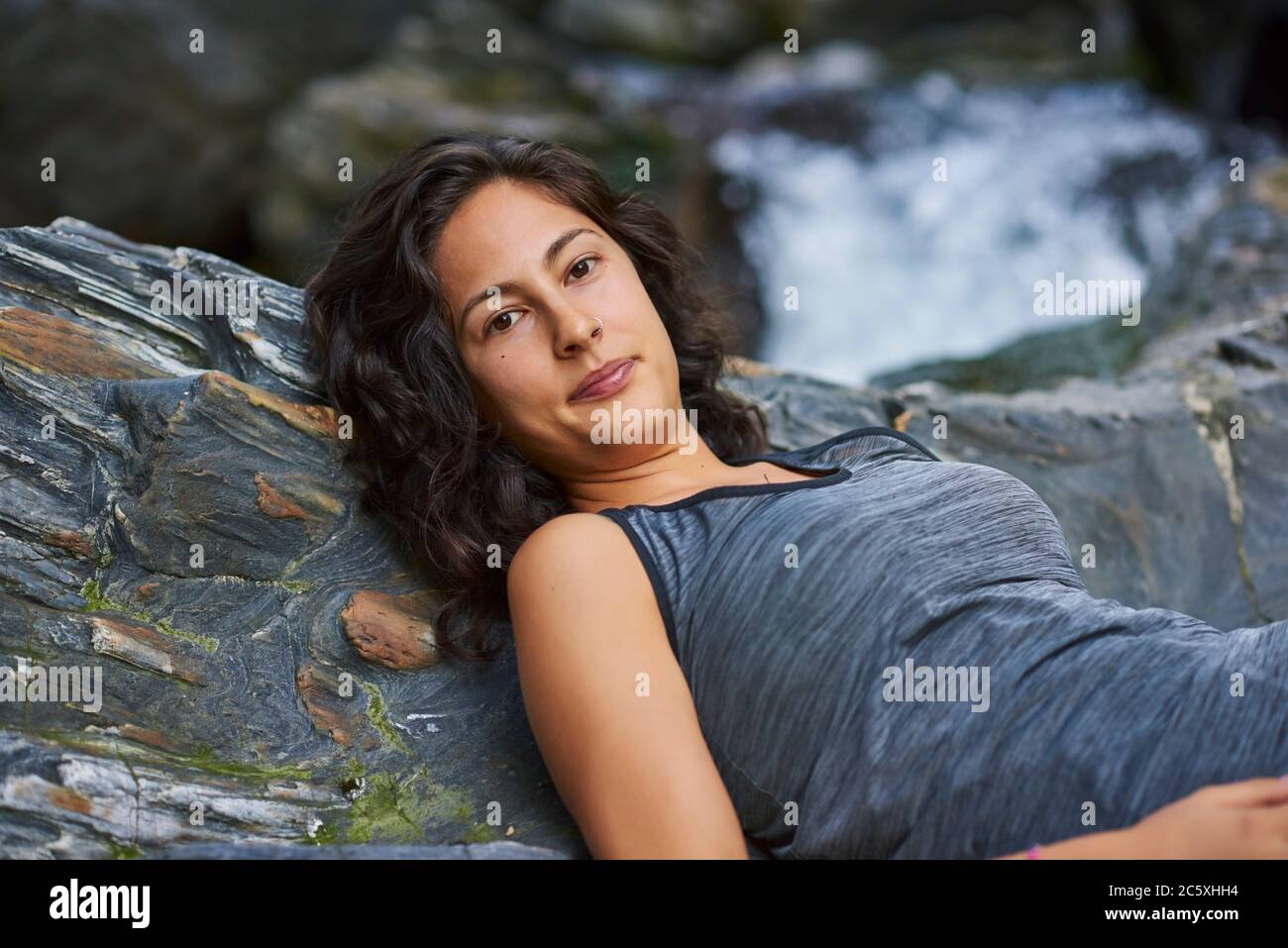 Femme couché sur un rocher dans une rivière. Elle est heureuse Banque D'Images