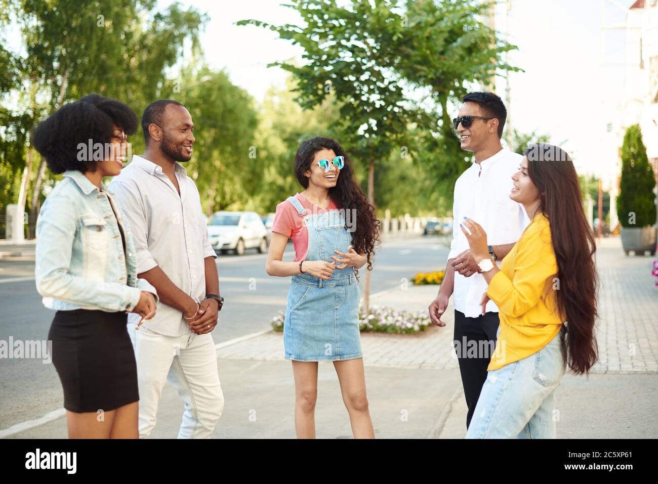 Concept de « Bonding Outdoors » pour les jeunes de groupe divers. Communication des amis de différentes races sur le fond de la ville et de la rue. Banque D'Images