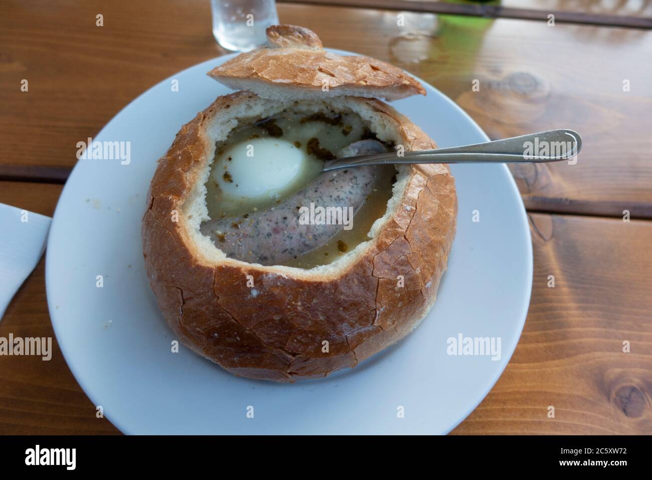 Soupe traditionnelle polonaise Zurek sour dans une boule de pain avec œufs et saucisses à l'intérieur, servie dans le restaurant Karczma Spalska. Spala Pologne centrale Banque D'Images