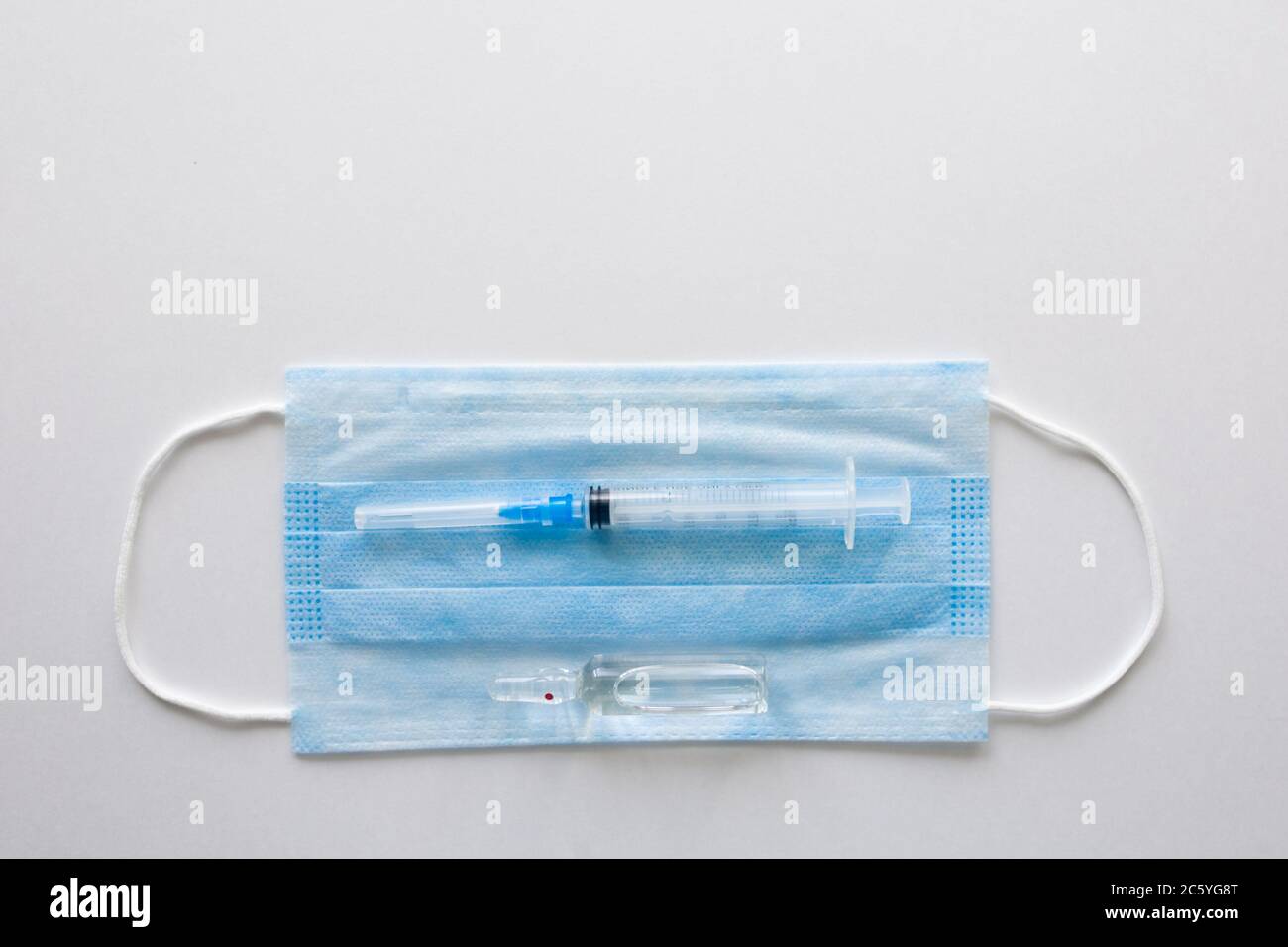 Masque médical antiviral pour la protection contre COVID-19. Bandage respiratoire médical visage sur fond blanc avec seringue. Banque D'Images