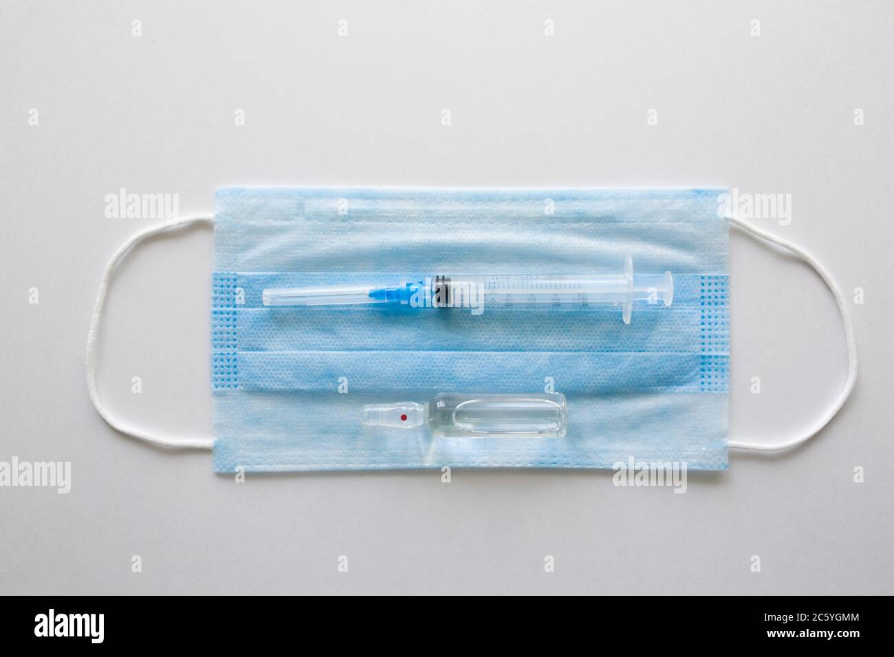 Masque médical antiviral pour la protection contre COVID-19. Bandage respiratoire médical visage sur fond blanc avec seringue. Banque D'Images