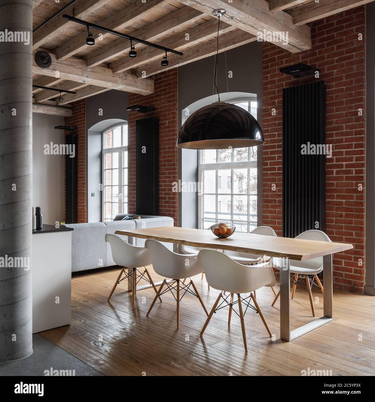 Cet appartement dispose d''un mur en briques industrielles, d''un plafond en bois et d''une table à manger Banque D'Images