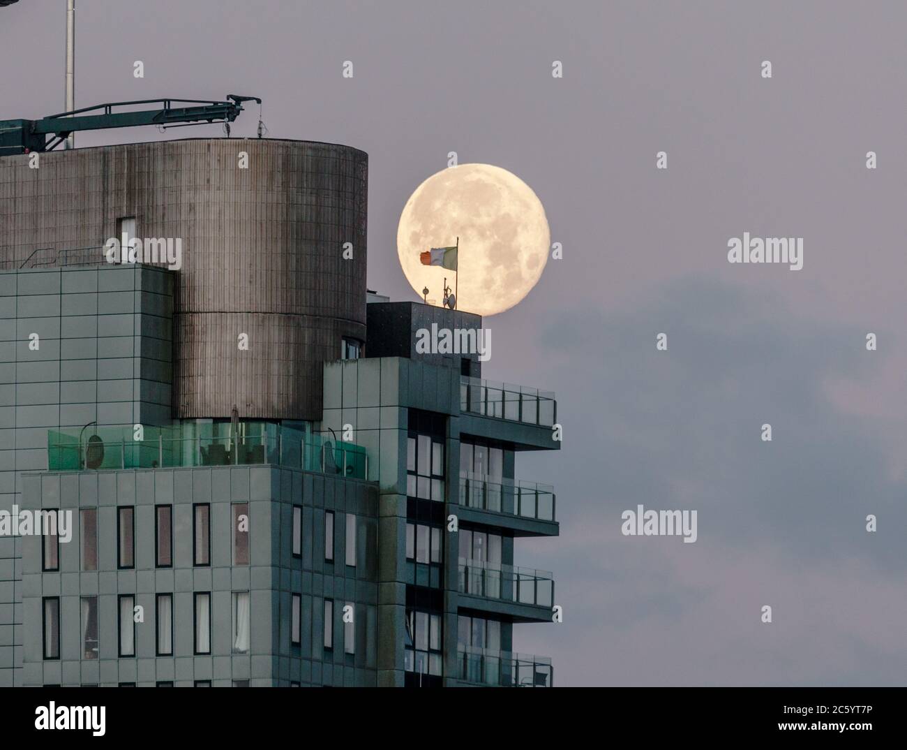 Cork, Cork, Irlande. 06e juillet 2020. Une pleine lune descend derrière le Tricolore irlandais qui flotte au-dessus de l'Elysian, le deuxième plus haut bâtiment d'Irlande à Cork, en Irlande. - crédit; David Creedon / Alamy Live News Banque D'Images