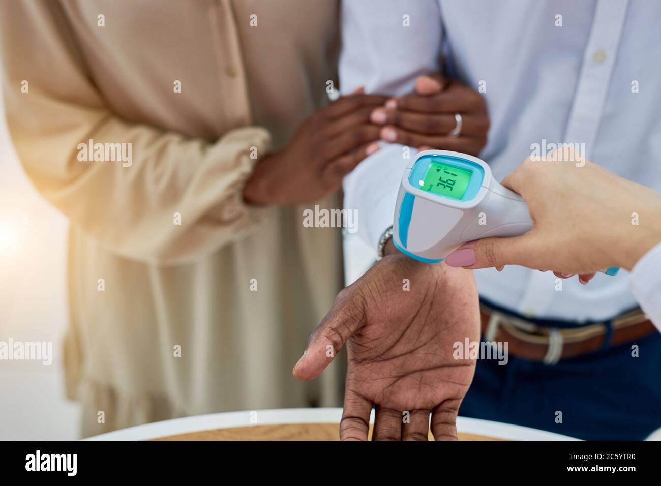 jeune couple marié africain est vérifié pour la température dans la concession, docteur femme utiliser un dispositif spécial, photo de près des mains Banque D'Images