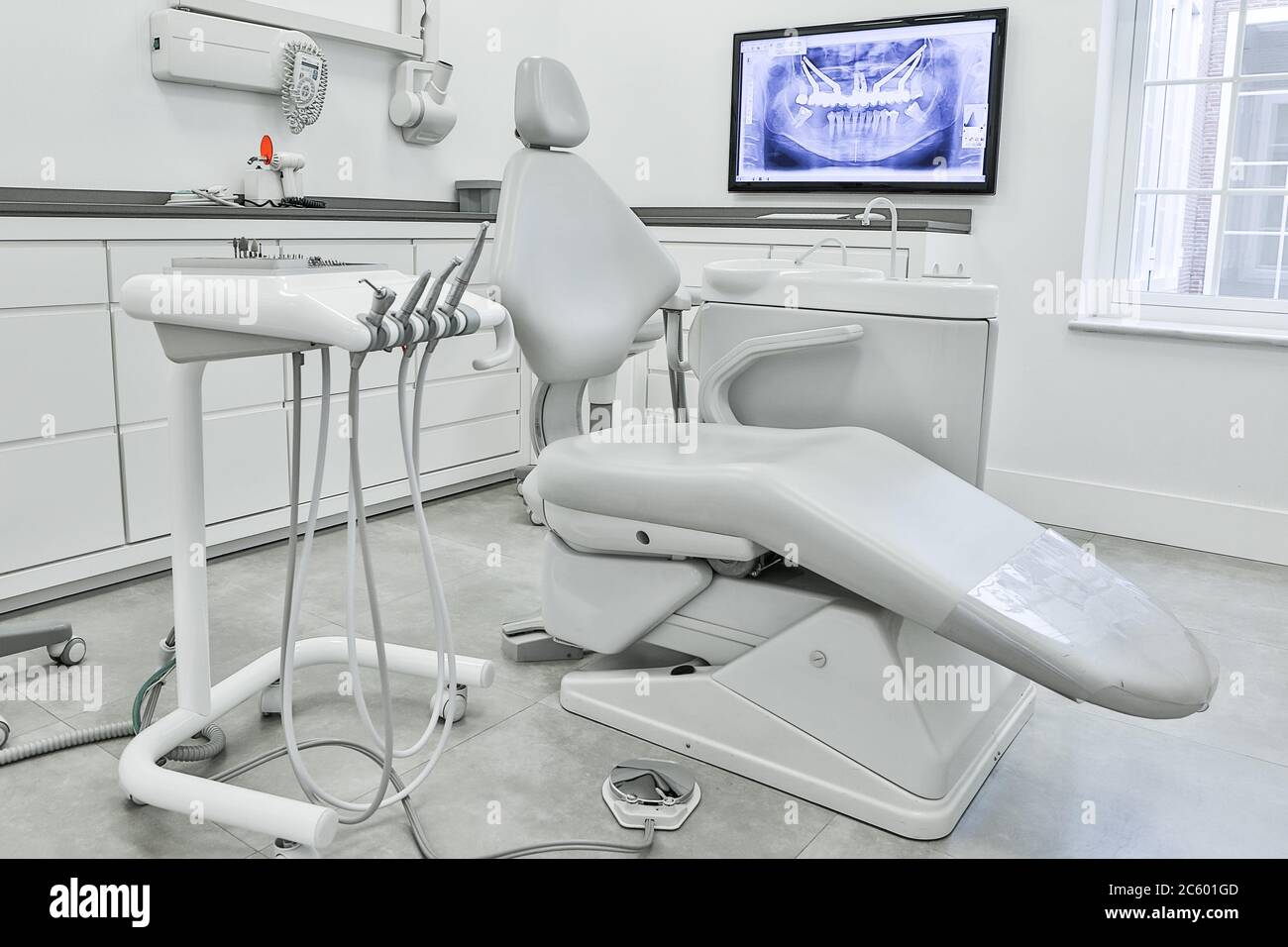 Chaise dentaire blanche et ensemble d'outils professionnels situés près des  armoires et d'un moniteur d'ordinateur avec rayons X dans le cabinet de  dentiste léger Photo Stock - Alamy