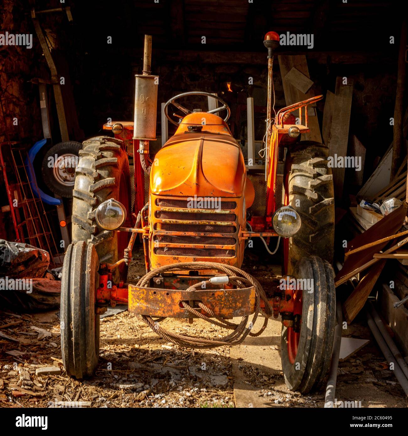 Tracteur orange inutilisé dans une ferme, Auvergne Rhône Alpes, France Banque D'Images