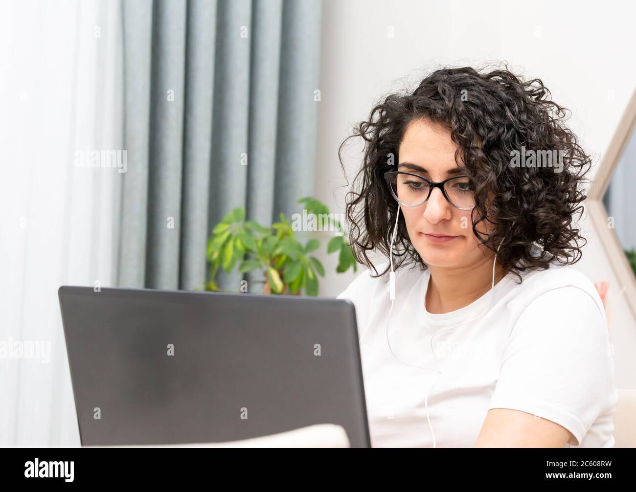 Belle femme dans un bureau moderne sur son lieu de travail parlant au téléphone au-dessus des écouteurs et travaillant sur un ordinateur portable. Banque D'Images