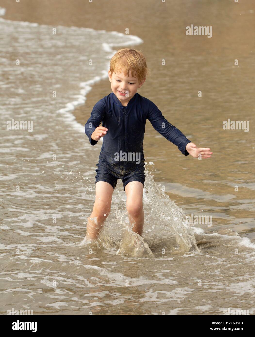 Jeune garçon d'âge préscolaire qui court et joue sur une plage de sable Banque D'Images