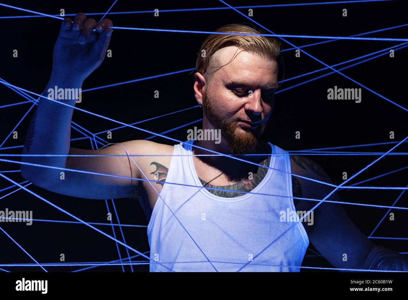 Image d'un homme tatoué emmêlé dans des fils de lumière néon Banque D'Images
