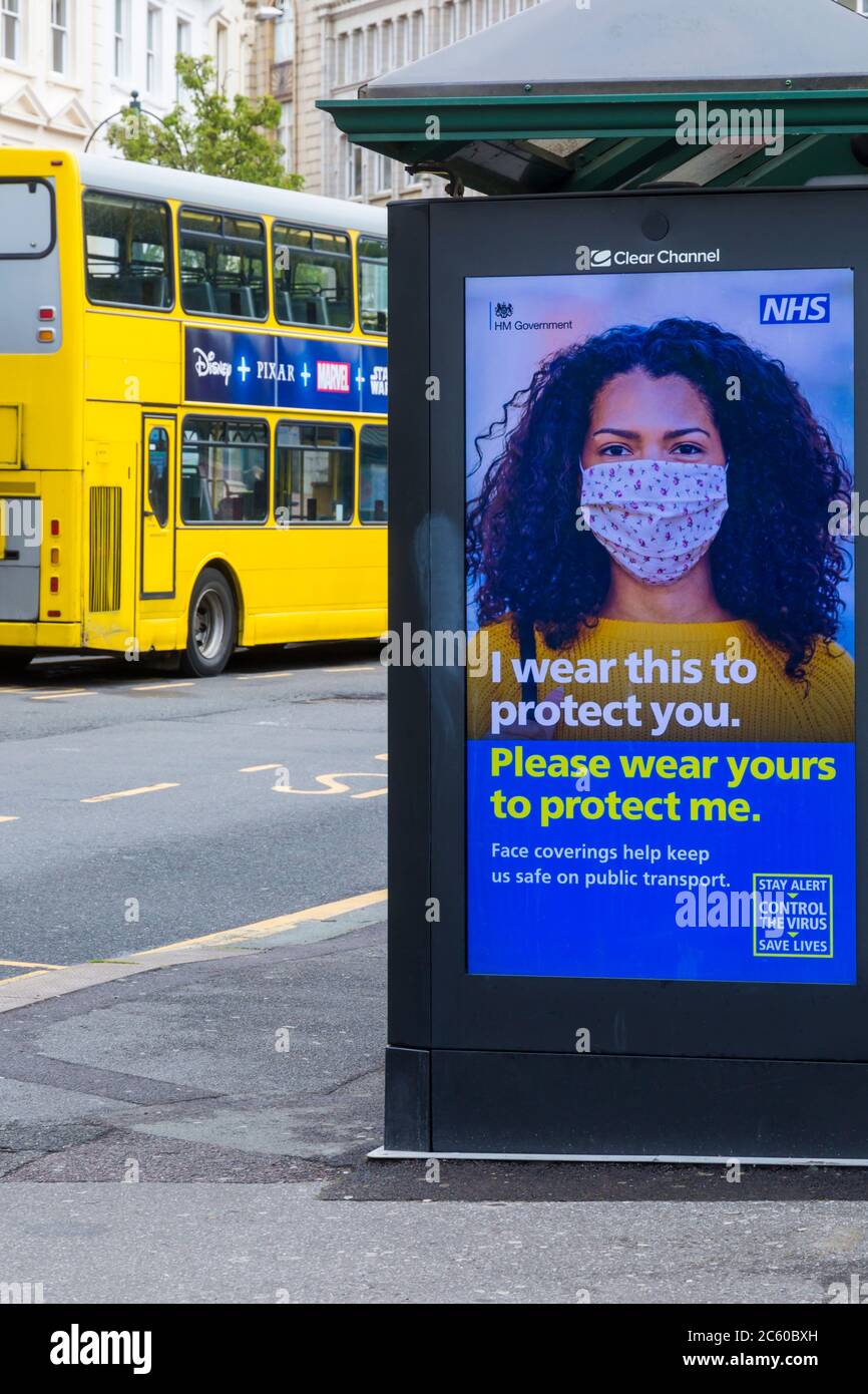Les revêtements de visage nous aident à rester en sécurité dans les transports publics rester alerte contrôler le virus sauver des vies poster avec bus jaune derrière à Bournemouth, Dorset Royaume-Uni Banque D'Images