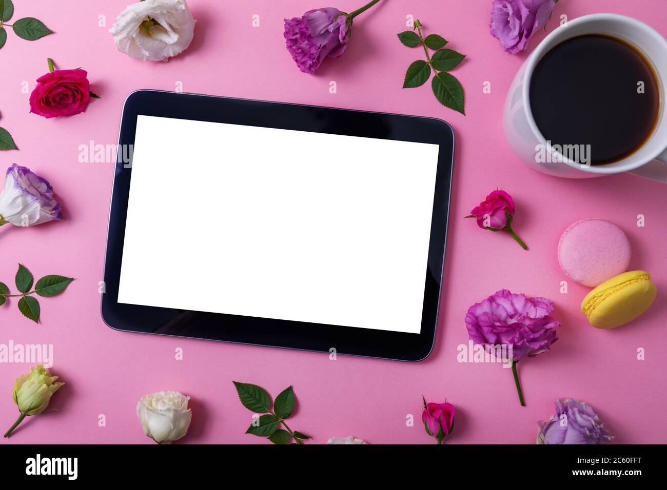tablette numérique avec écran vierge sur fond rose avec fleurs et tasse à café. vue du dessus Banque D'Images