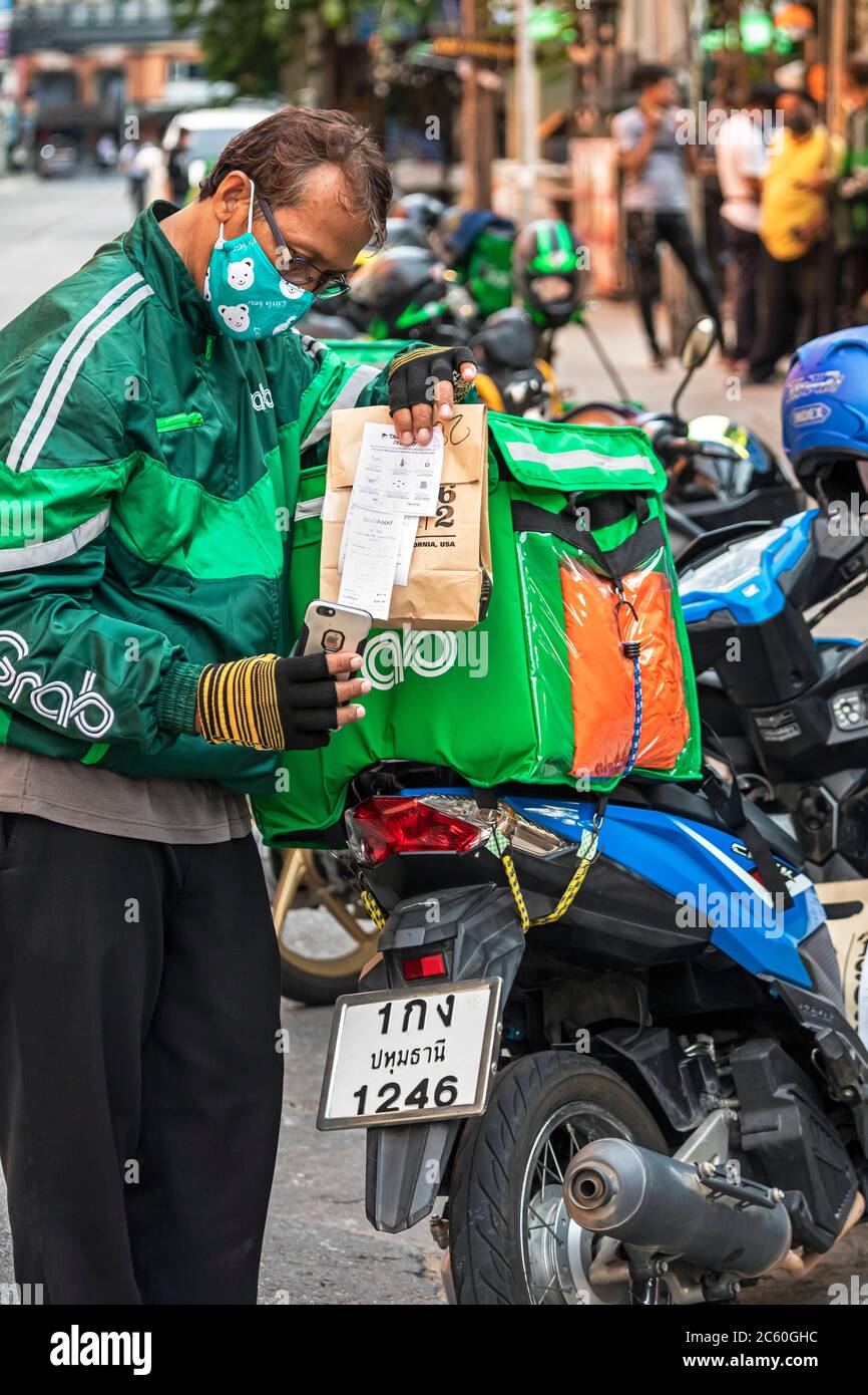 Prendre moto livraison cavalier portant un masque facial pendant la pandémie Covid 19, Bangkok, Thaïlande Banque D'Images