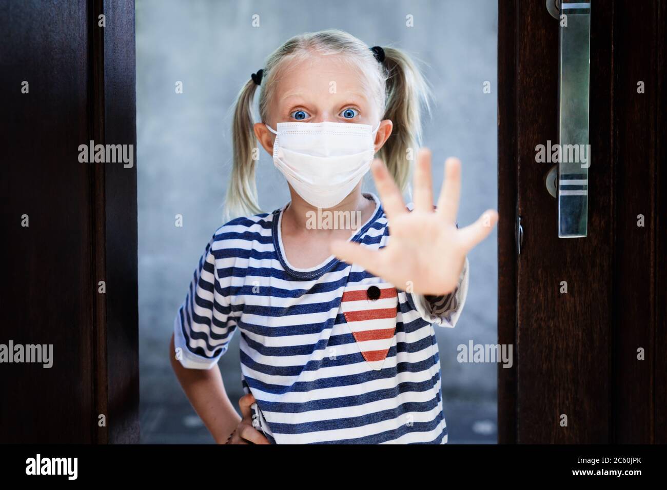 Petit enfant montrant le geste de la main Stop virus. Les enfants portant des masques médicaux sortent pour la promenade à l'extérieur après être restés à la maison en raison de l'activité interdite dans la rue. Banque D'Images