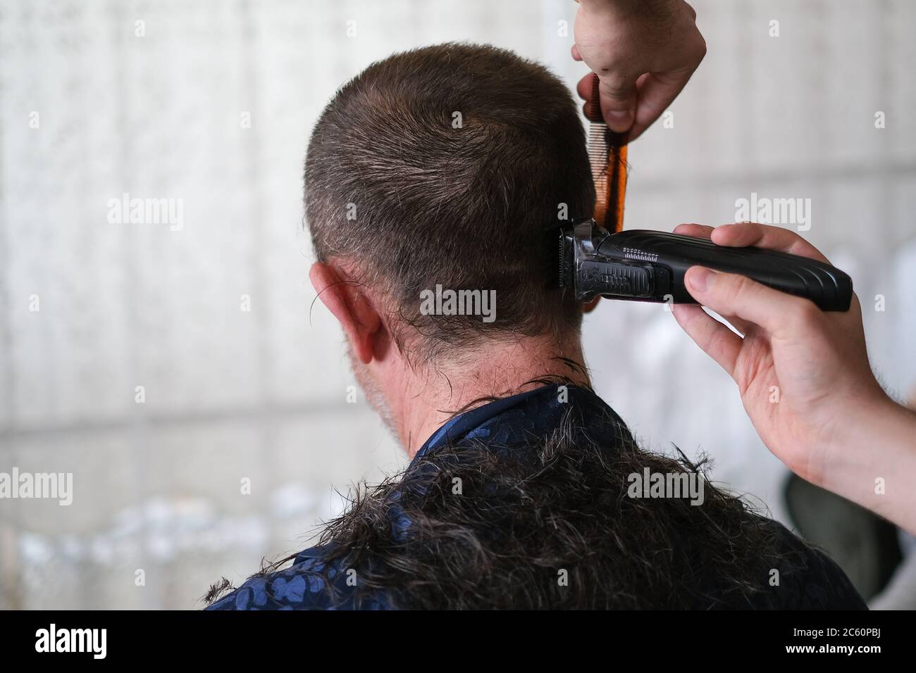 Le jeune homme coupe les cheveux du père avec une tondeuse à cheveux pendant l'isolement de quarantaine du coronavirus à la maison .concept de coupe de cheveux à la maison. Banque D'Images