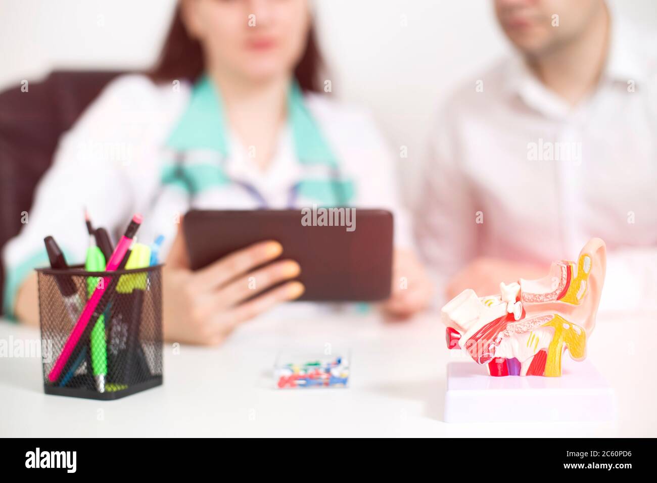 Le médecin otolaryngologiste féminin montre sur le comprimé des informations sur la structure de l'oreille, de la gorge et du nez. Concept de chirurgie ORL, contexte Banque D'Images