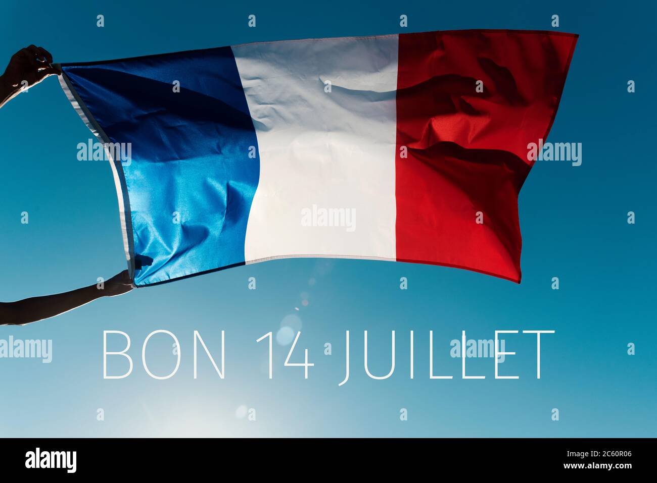 Homme portant un drapeau français agitant sur le vent et le texte bon 14 juillet, heureux 14 juillet, la journée nationale de la France écrite en français, contre le blu Banque D'Images