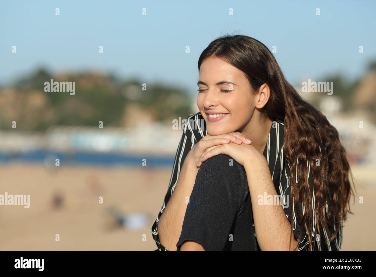 Bonne fille fermant les yeux se reposant sur la plage un jour ensoleillé Banque D'Images
