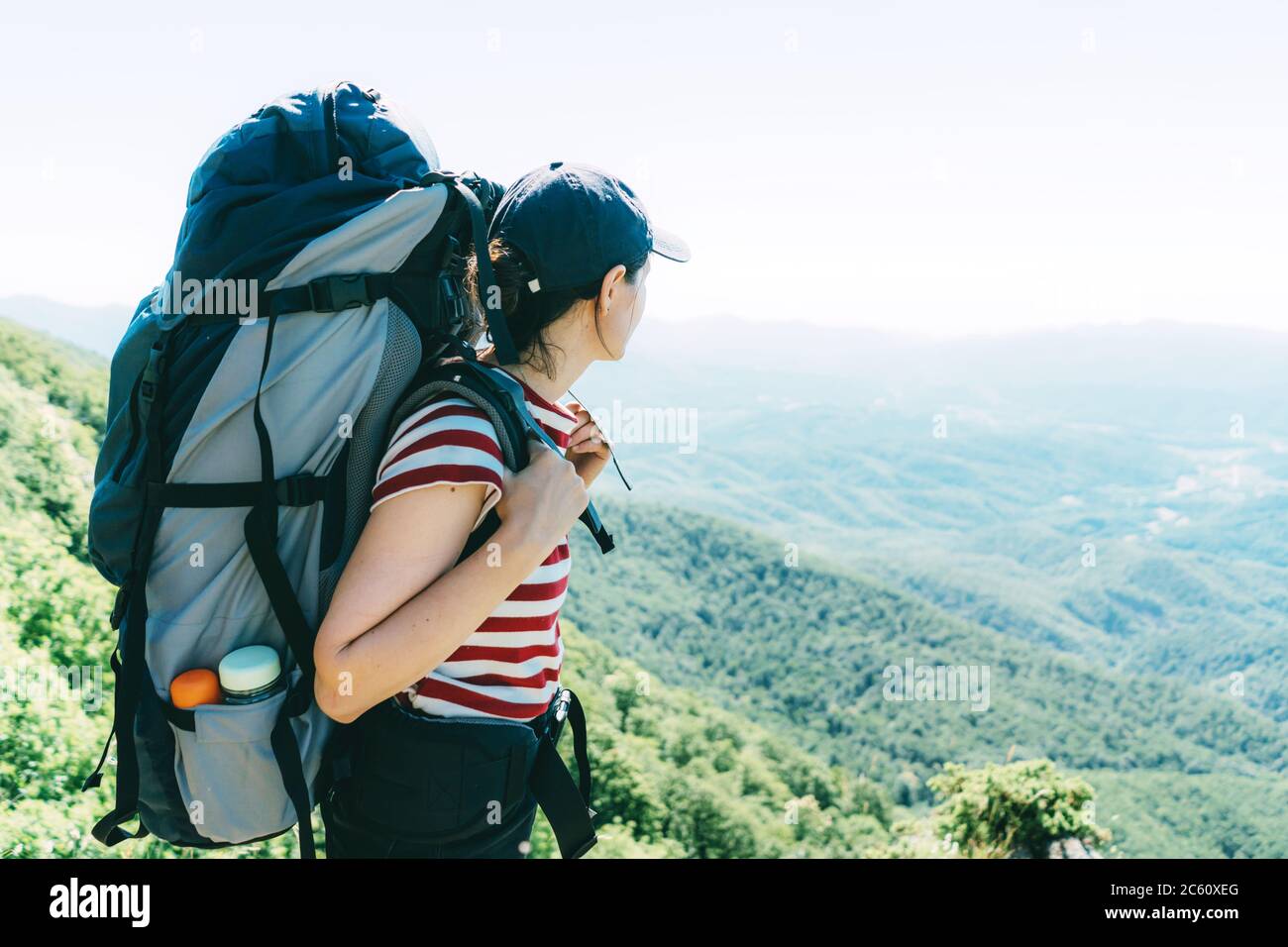 Une femme touriste avec un grand sac à dos de camping sur une expédition se tient sur le dessus et regarde le paysage. Banque D'Images