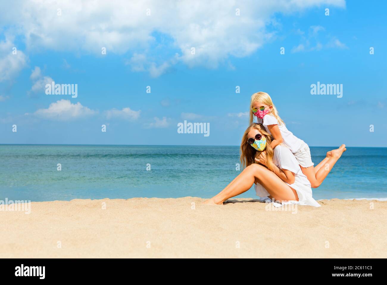 Mère, enfant dans les masques ont l'amusement sur la plage de mer. Nouvelles règles pour le port de revêtements de façade en tissu dans les lieux publics. Croisière annulée, circuit à échéance coronavirus COVID 19. Banque D'Images