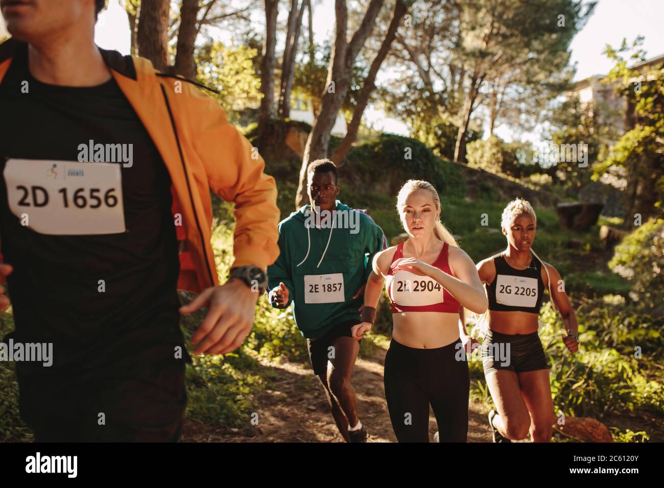 Groupe multiethnique d'athlètes qui s'entraînent sur un sentier de montagne. Hommes et femmes qui se disputer une course de championnat de marathon de cross-country. Banque D'Images