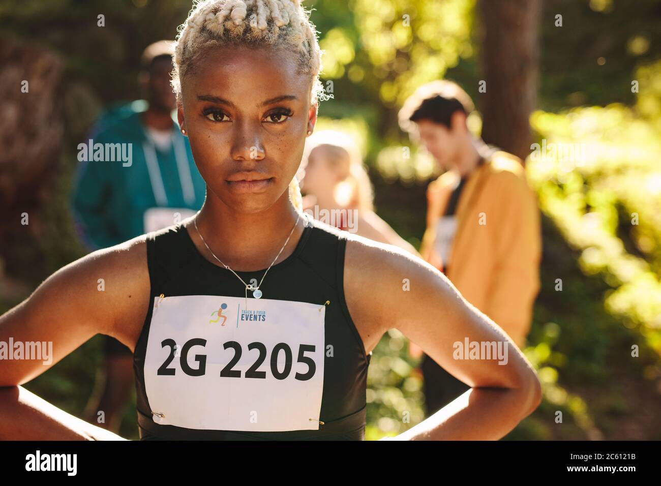 Coureur de marathon de fond plein air en toute confiance, regardant la caméra avec les mains sur les hanches. Sportswoman debout à l'extérieur avec ses membres de club re Banque D'Images