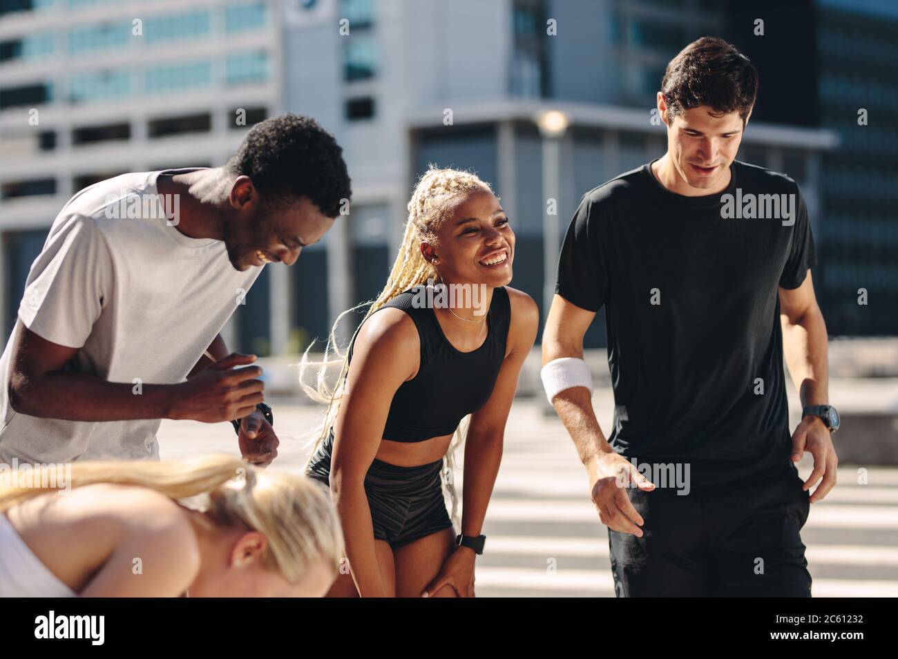 Amis multi-ethniques à l'extérieur dans la ville après l'entraînement. groupe de fitness se reposant et souriant après l'entraînement. Banque D'Images