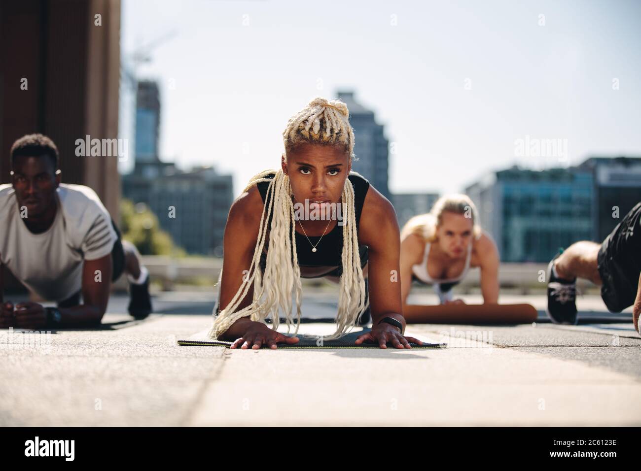 Groupe de personnes faisant de l'exercice de planche sur le tapis de fitness à l'extérieur. Entraînement de groupe sportif en ville. Banque D'Images