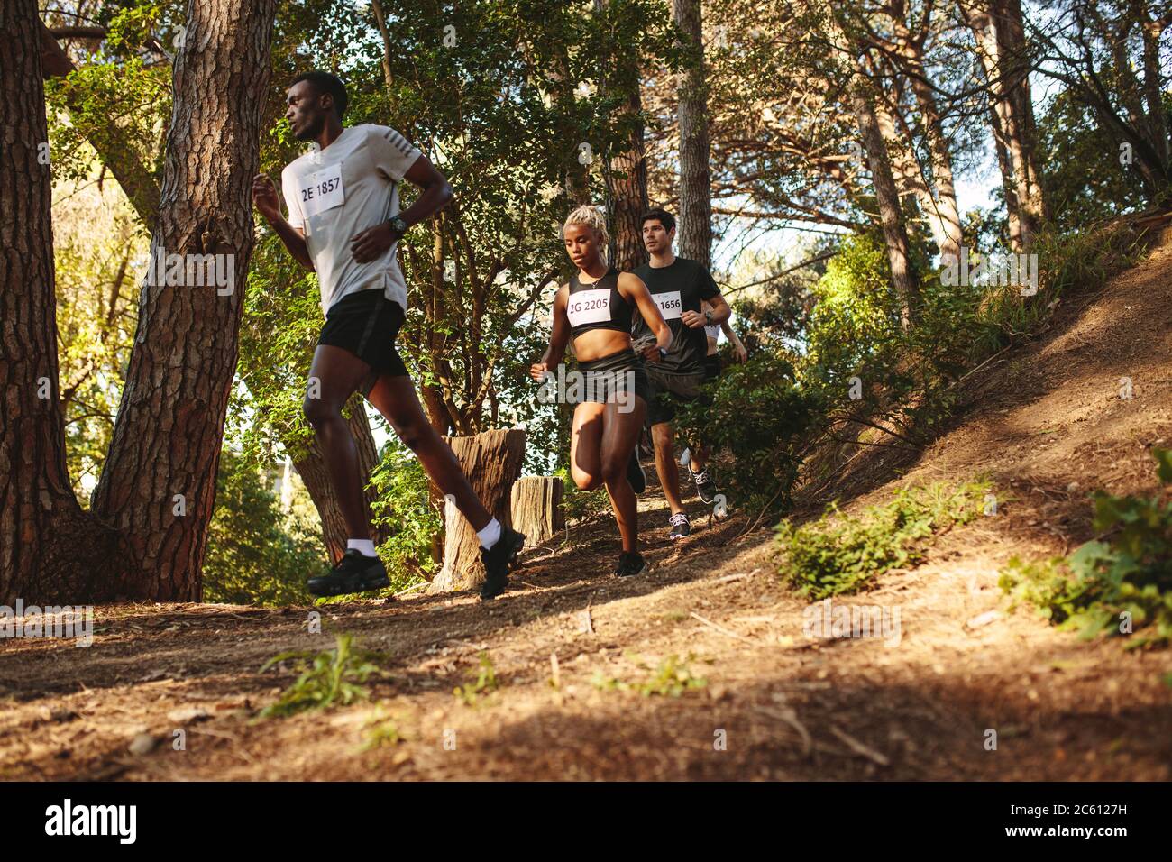 Les athlètes qui descendent sur une colline sur un sentier de montagne. Homme et femme coureur course à pied dans une course de marathon de cross-country. Banque D'Images