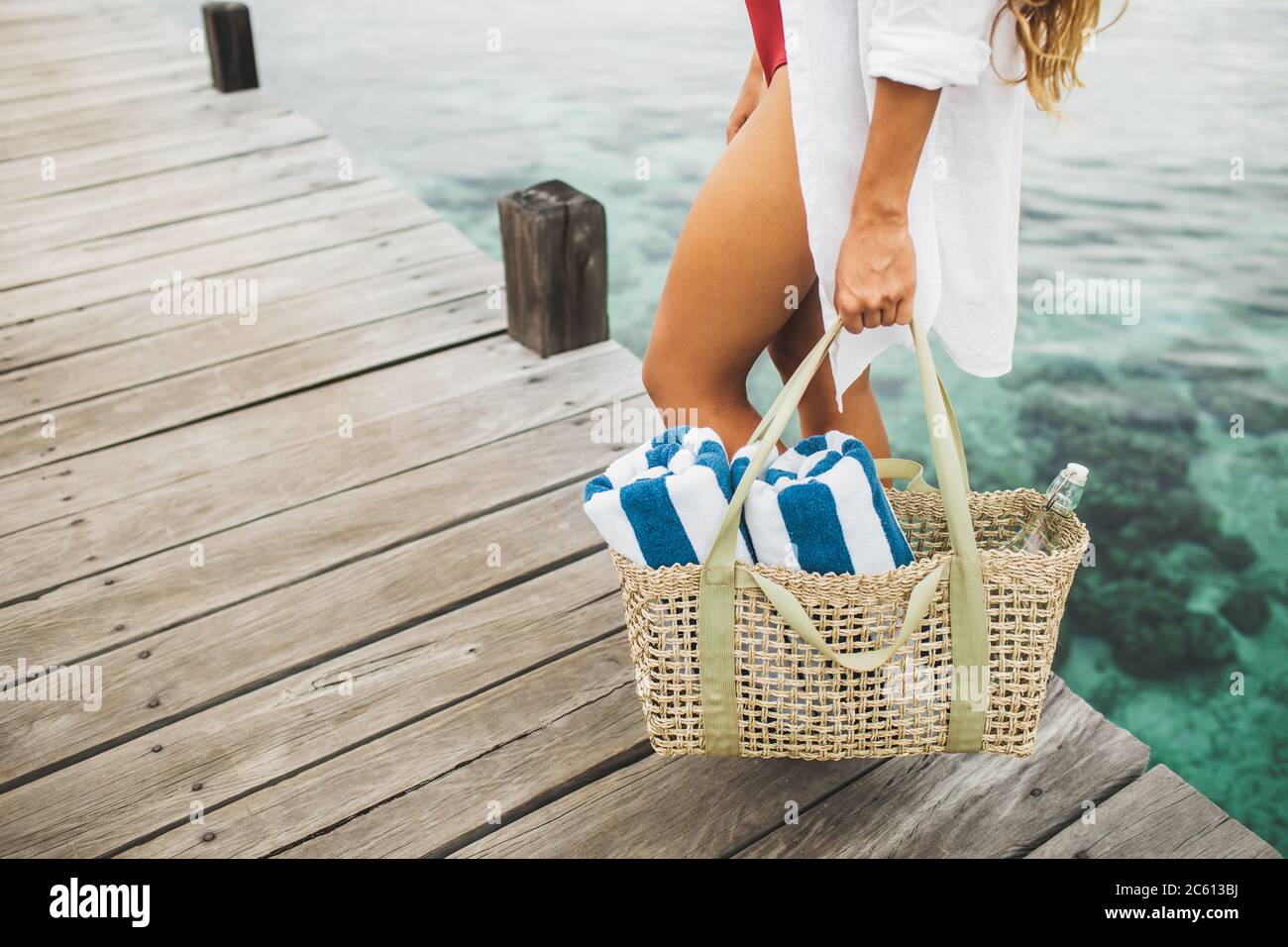 Femme tenant un sac en osier avec deux serviettes de plage et une bouteille  de verre pour l'eau et aller à la plage. Concept écologique et zéro déchet  Photo Stock - Alamy