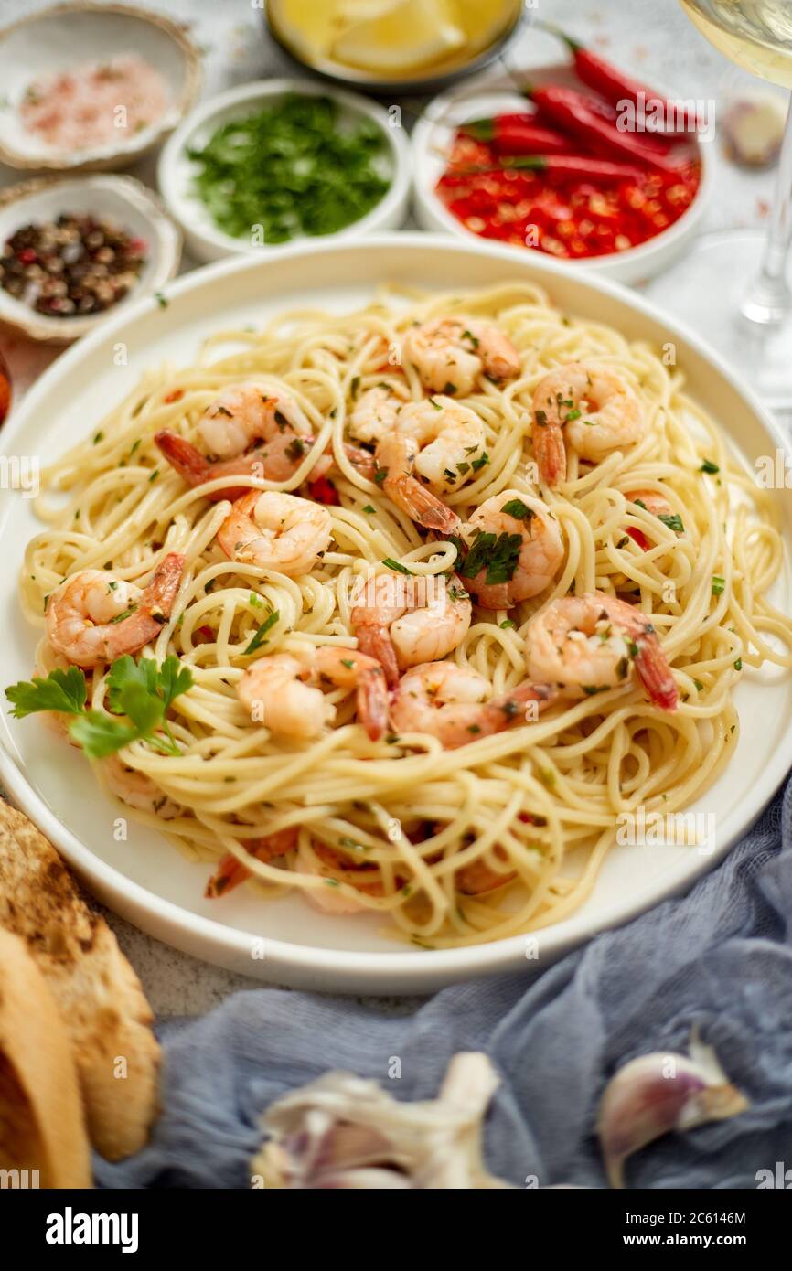 Spaghetti aux crevettes sur plaque de céramique blanche et servis avec un verre de vin blanc Banque D'Images