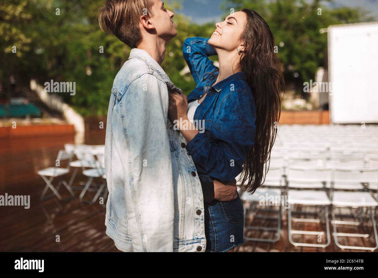 Portrait d'un jeune couple souriant debout et enfermé sous la pluie le jour dans le parc Banque D'Images