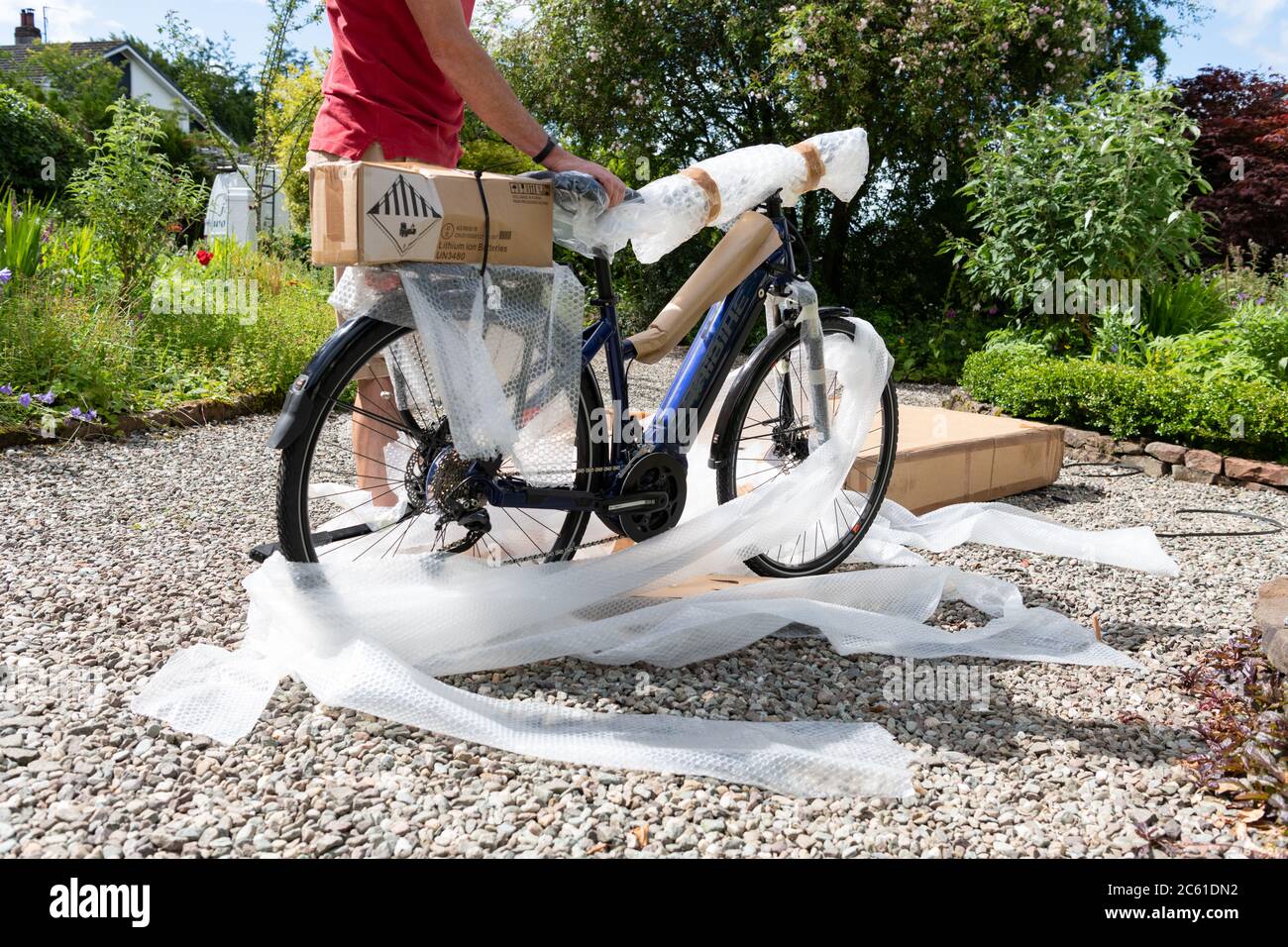 Livraison à domicile de vélo électrique ebike commandé en ligne pendant le verrouillage du coronavirus - vélo sorti de la boîte à vélo et de déballer le film à bulles - Royaume-Uni Banque D'Images