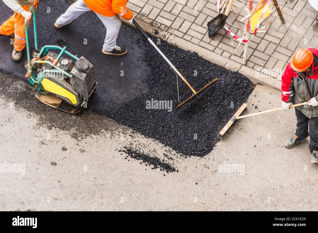 Machine manuelle pour ouvrier de pavage d'asphalte, les ouvriers nivelent la couche d'asphalte avant de tabourer la vue du dessus Banque D'Images