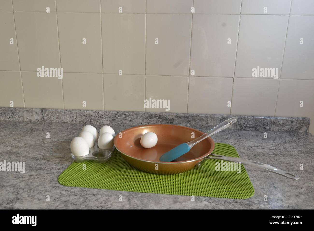 Poêle à frire avec des oeufs encore dans leur coquille, à préparer sur une nappe verte, sur une table en granit et en céramique de fond de carreaux, Brésil, Amérique du Sud Banque D'Images