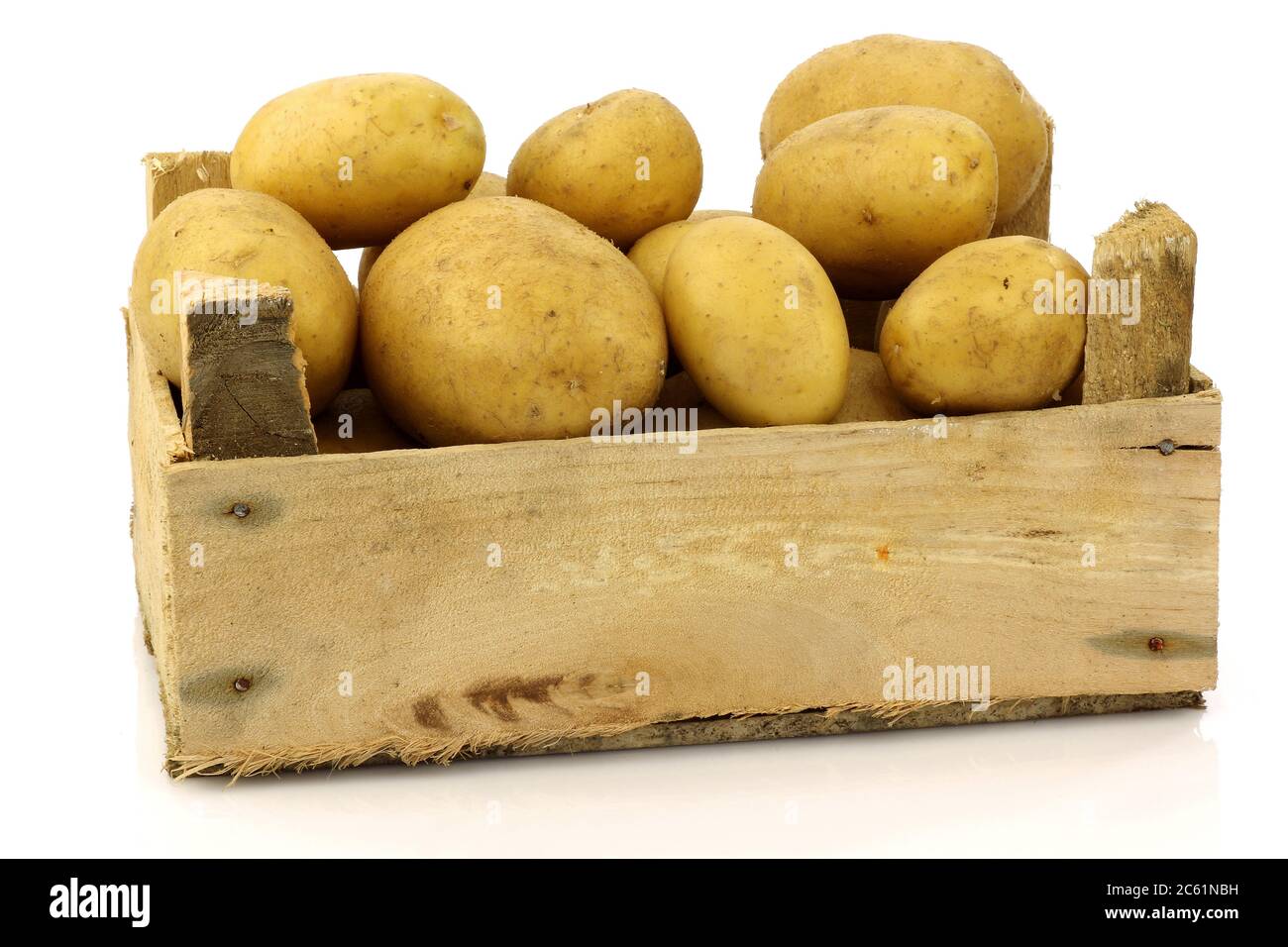 bouquet de pommes de terre fraîchement récoltées dans une boîte en bois et quelques-unes à côté sur fond blanc Banque D'Images