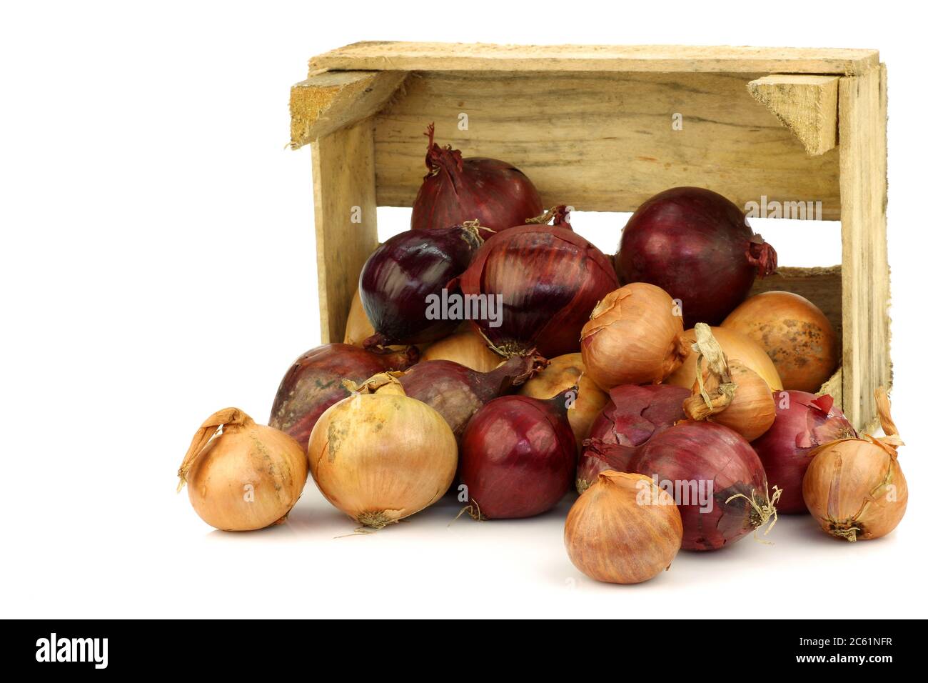 oignons rouges et bruns dans une boîte en bois sur fond blanc Banque D'Images