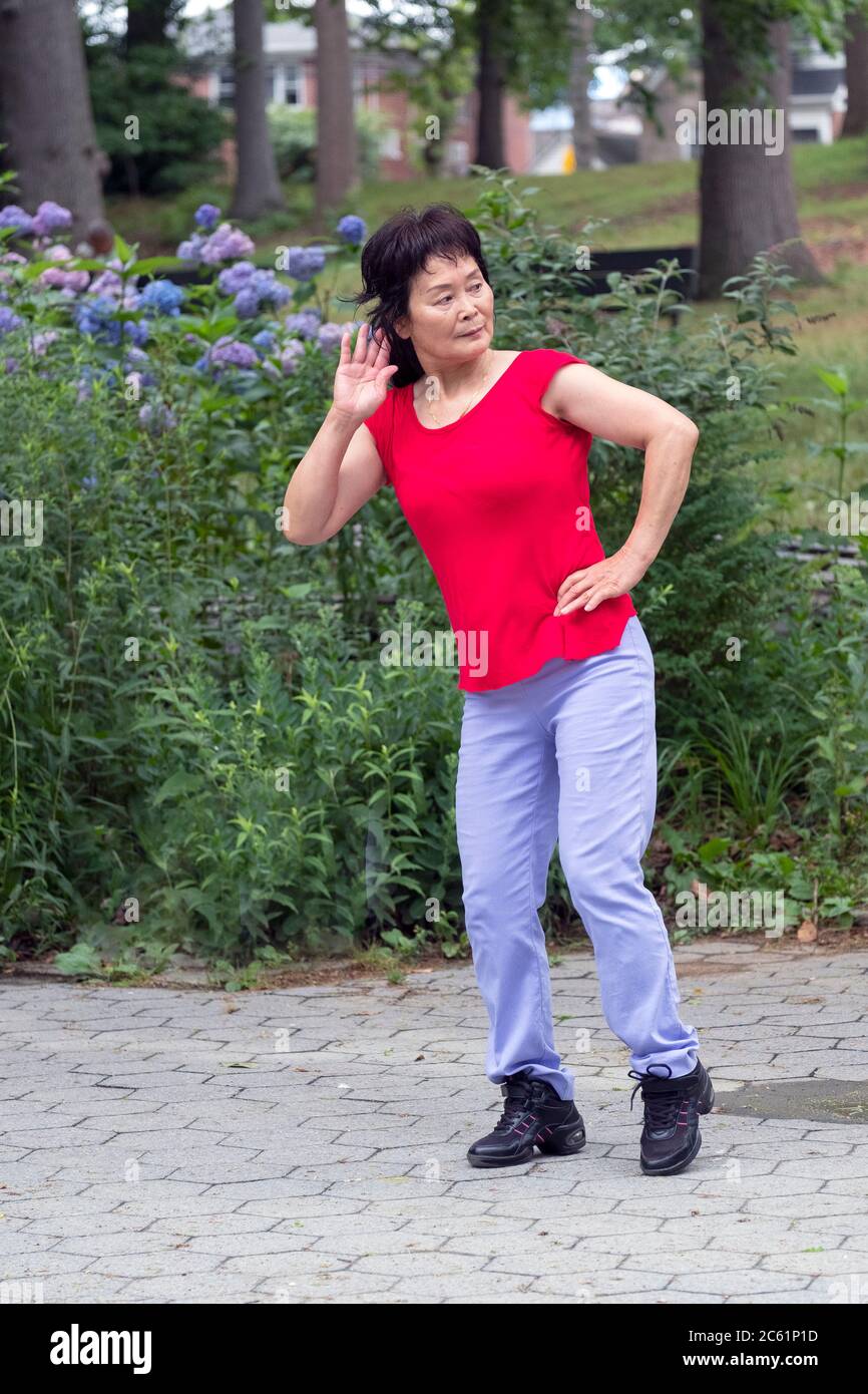 Une femme asiatique américaine danse vigoureusement à la musique chinoise pendant plus de 30 minutes. À Kissena Park, Flushing, New York. Banque D'Images