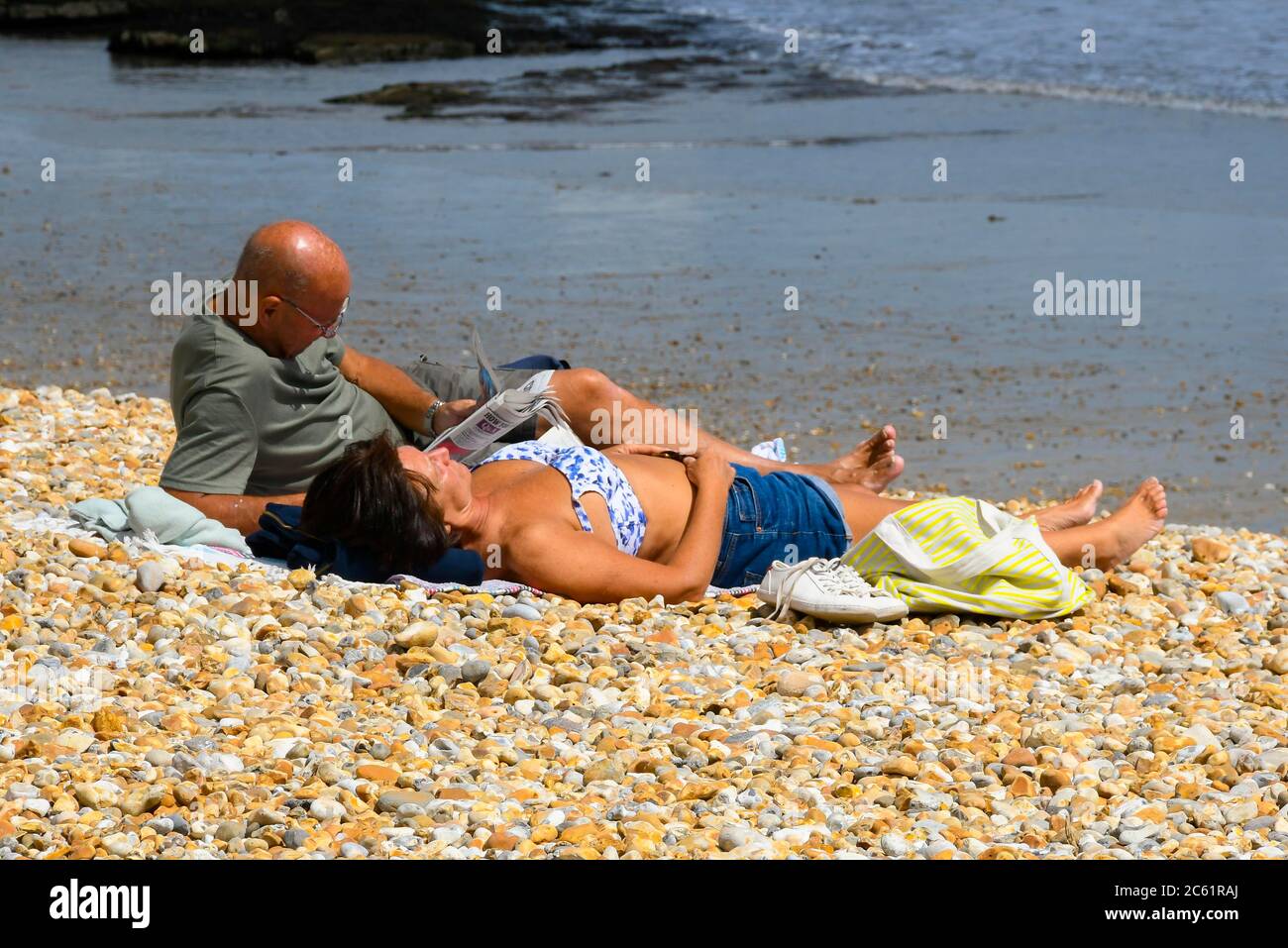 Lyme Regis, Dorset, Royaume-Uni. 6 juillet 2020. Météo britannique: Un couple de bains de soleil sur la plage à la station balnéaire de Lyme Regis à Dorset, sur une journée de chaudes périodes ensoleillées. Crédit photo : Graham Hunt/Alay Live News Banque D'Images
