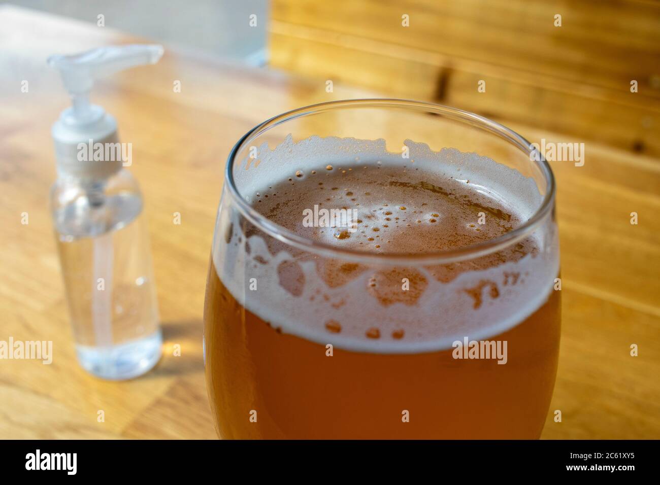 Gros plan sur un verre à bière IPA avec une bouteille de pompe d'assainisseur pour les mains dans un bar rouvert pendant la réouverture du coronavirus COVID-19 pandémique Banque D'Images