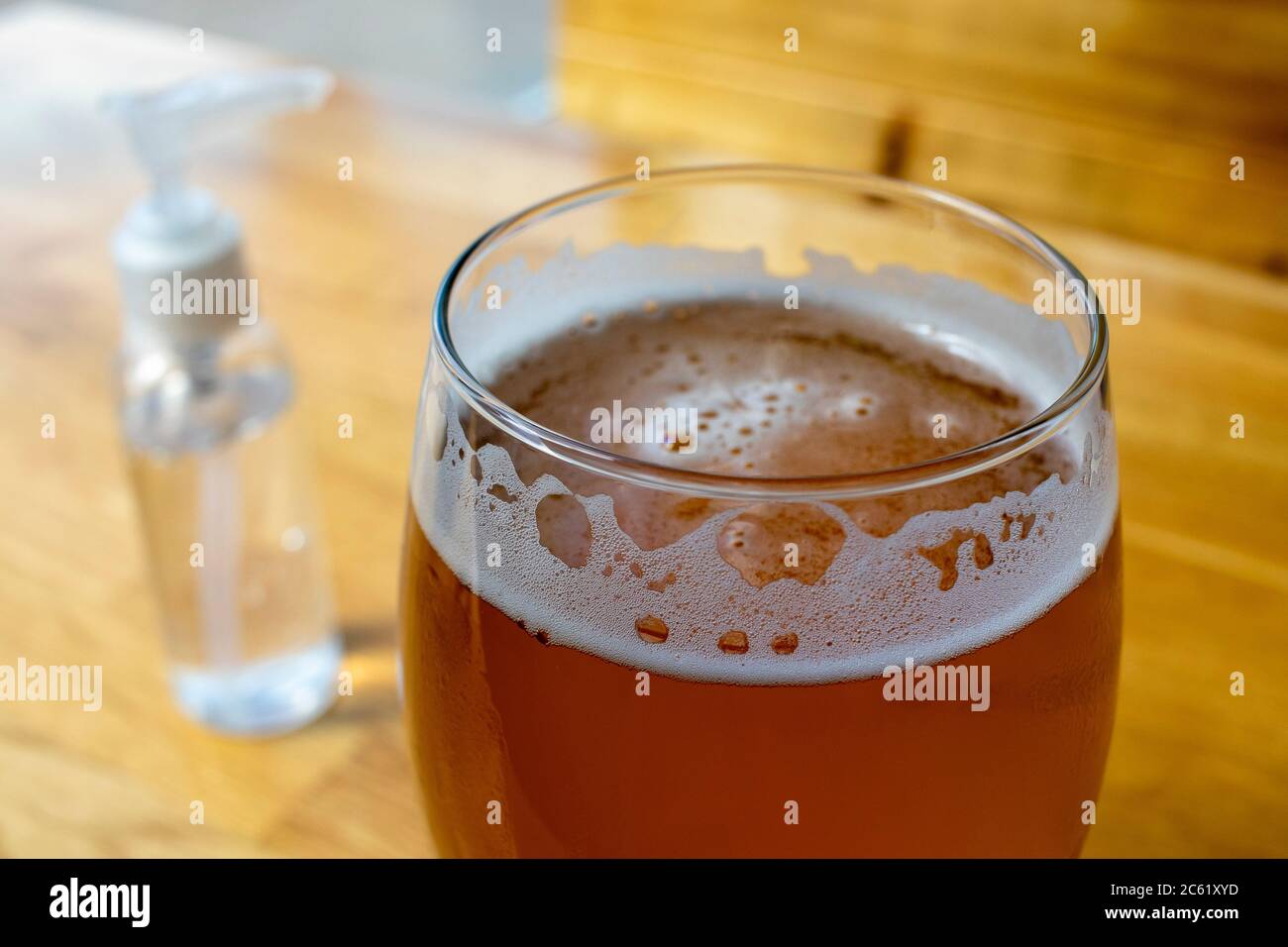 Gros plan sur un verre à bière IPA avec un flacon de pompe à gel désinfectant pour les mains mis de côté dans un bar rouvert pendant la réouverture du coronavirus COVID-19 pandémique Banque D'Images