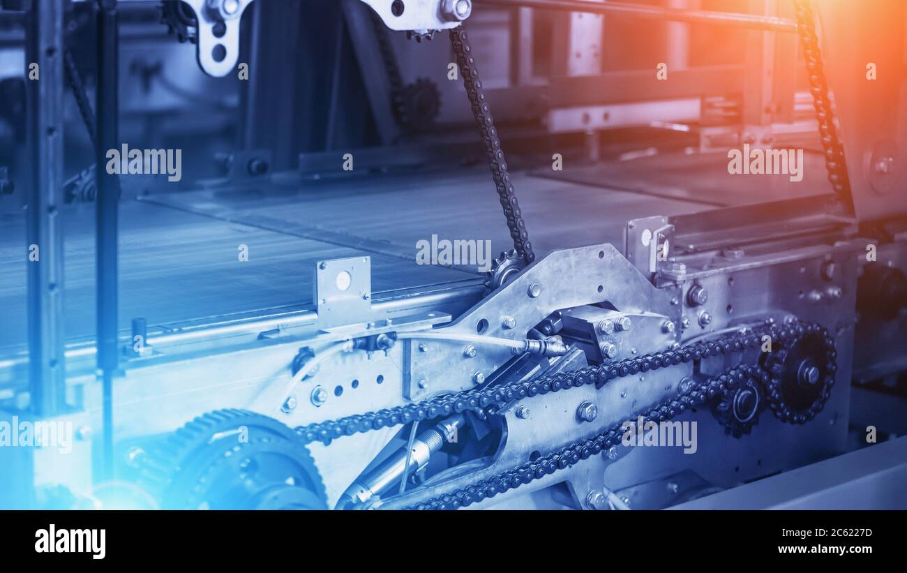 Historique de l'industrie, tapis transporteur industriel vide avec chaînes et mécanismes en métal de couleur bleue et effets de lumière rouge et bleue, espace de copie pour le texte. Banque D'Images