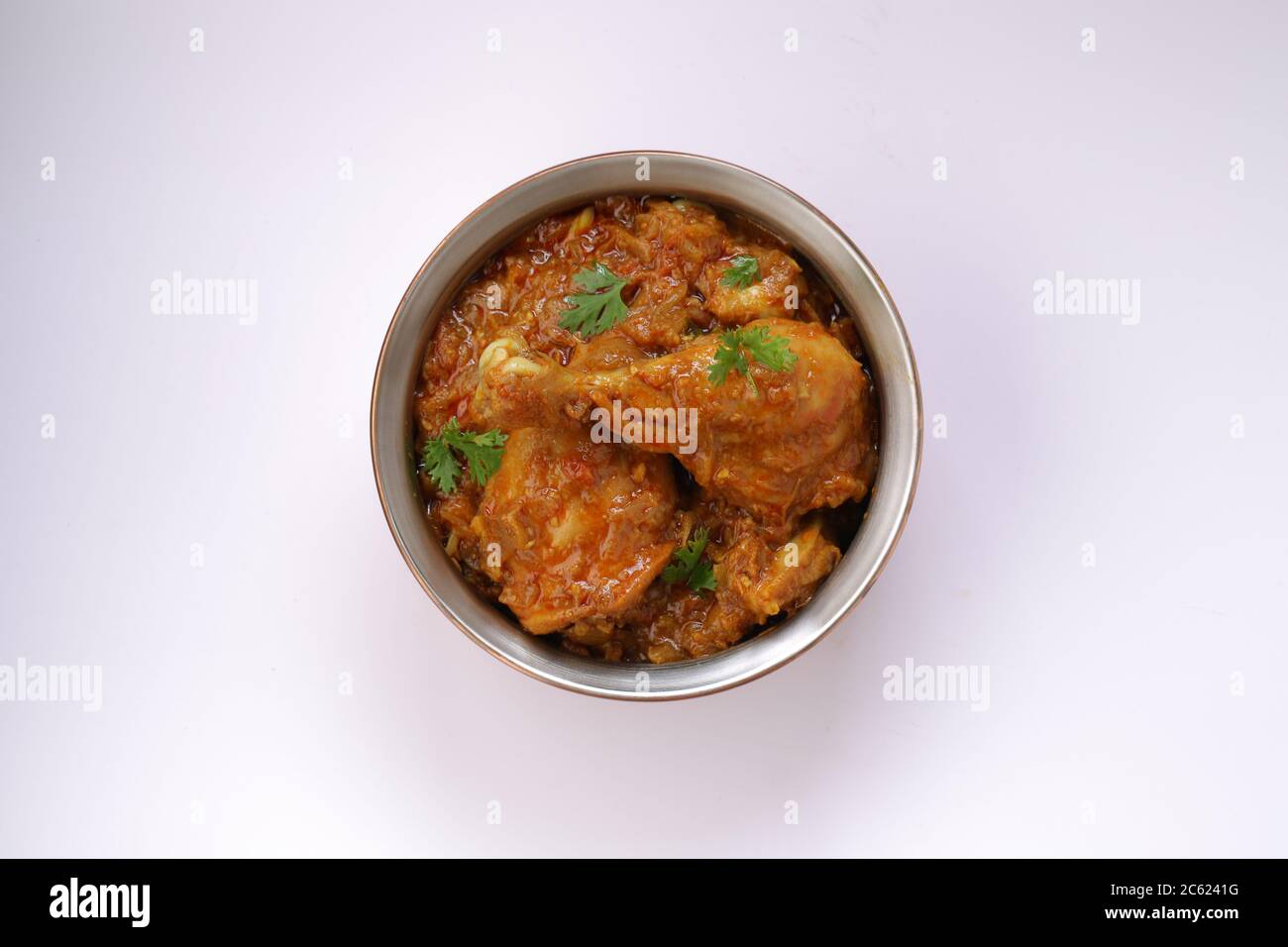Vue de dessus du curry de poulet ou du masala, plat piquant de jambe de poulet rougeâtre garni de feuilles de coriandre, qui est traditionnellement arrangé Banque D'Images