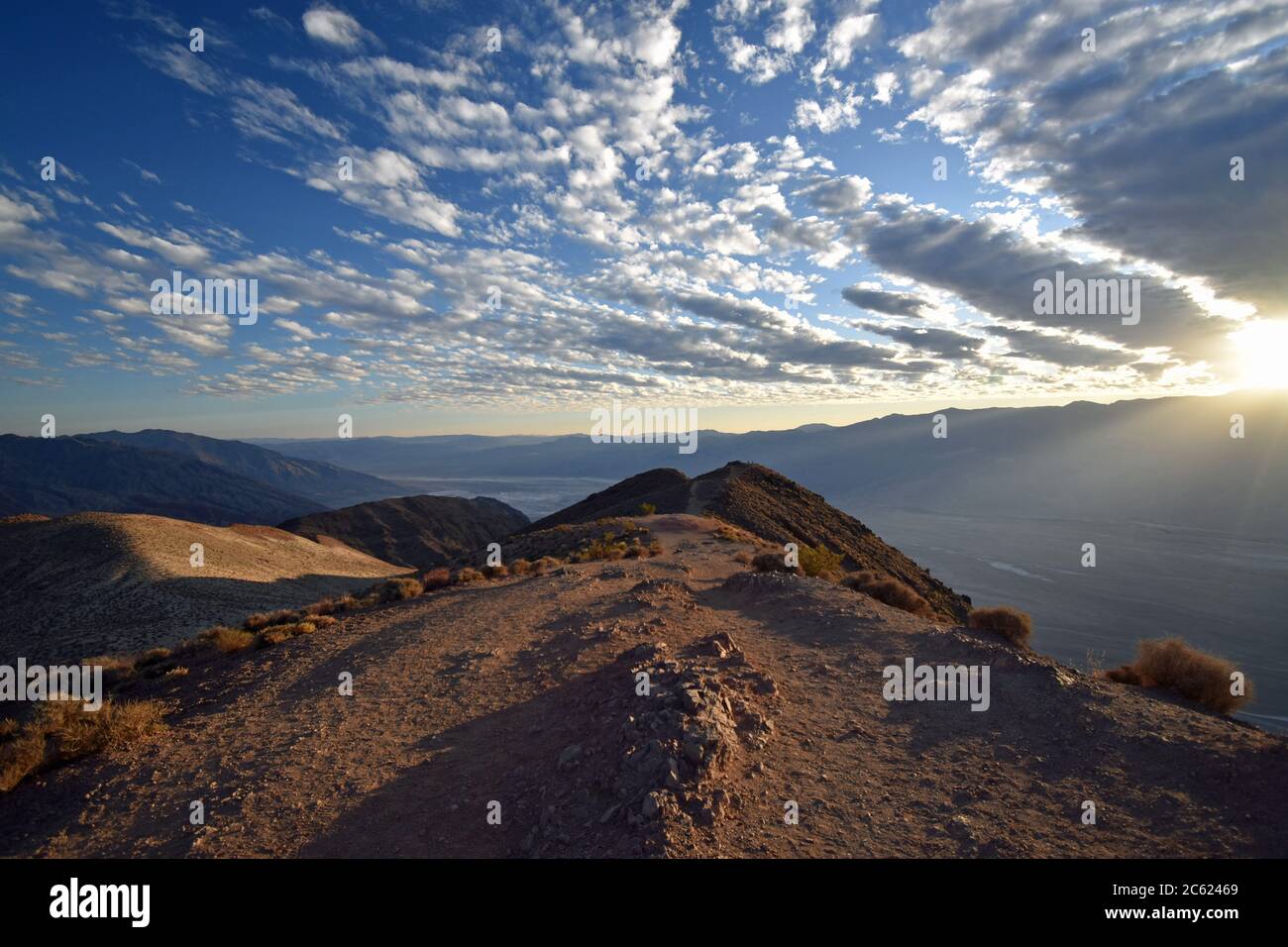 Coucher de soleil à Dantes, vue sur la Vallée de la mort. Un chemin mène vers le bord de la chaîne de montagnes. Le soleil couchant traverse les nuages. Banque D'Images