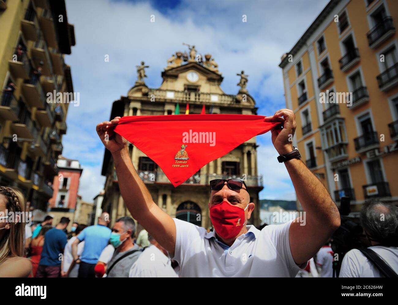 Un homme porte un foulard rouge sur la place de la mairie de Pampelune.les  habitants de la ville espagnole de Pampelune, dans le nord de l'Espagne,  vêtus de vêtements blancs et de