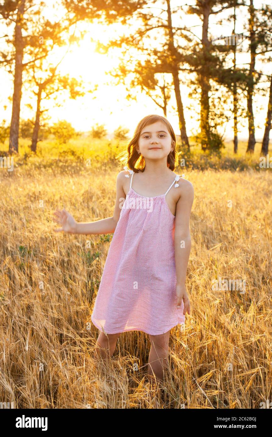 Une drôle de fille danse sur une promenade à travers le champ au coucher du soleil. Le concept de l'enfance réelle, détox numérique, vacances d'été, bonheur. Banque D'Images