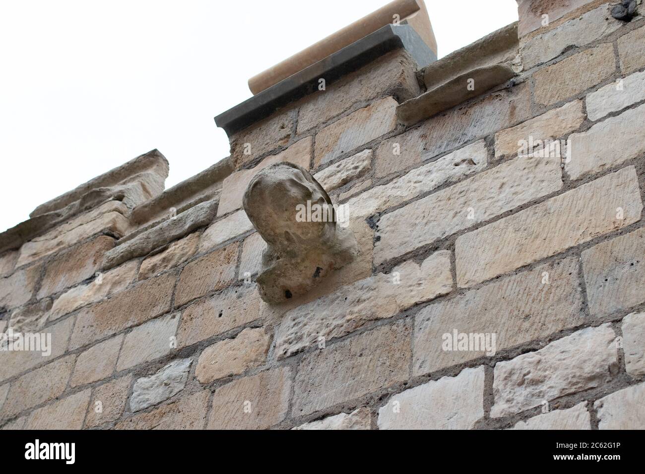 Une statue de style gargouille qui sort du mur d'Eastgate qui a été rénovée dans le cadre du projet Lincoln Connected. Il est visible sur l'un des murs autour de la cathédrale de Lincoln. On pense qu'il est sculpté comme un avertissement à une religion de rester loin quand ils ont été interdits de la cathédrale. Banque D'Images