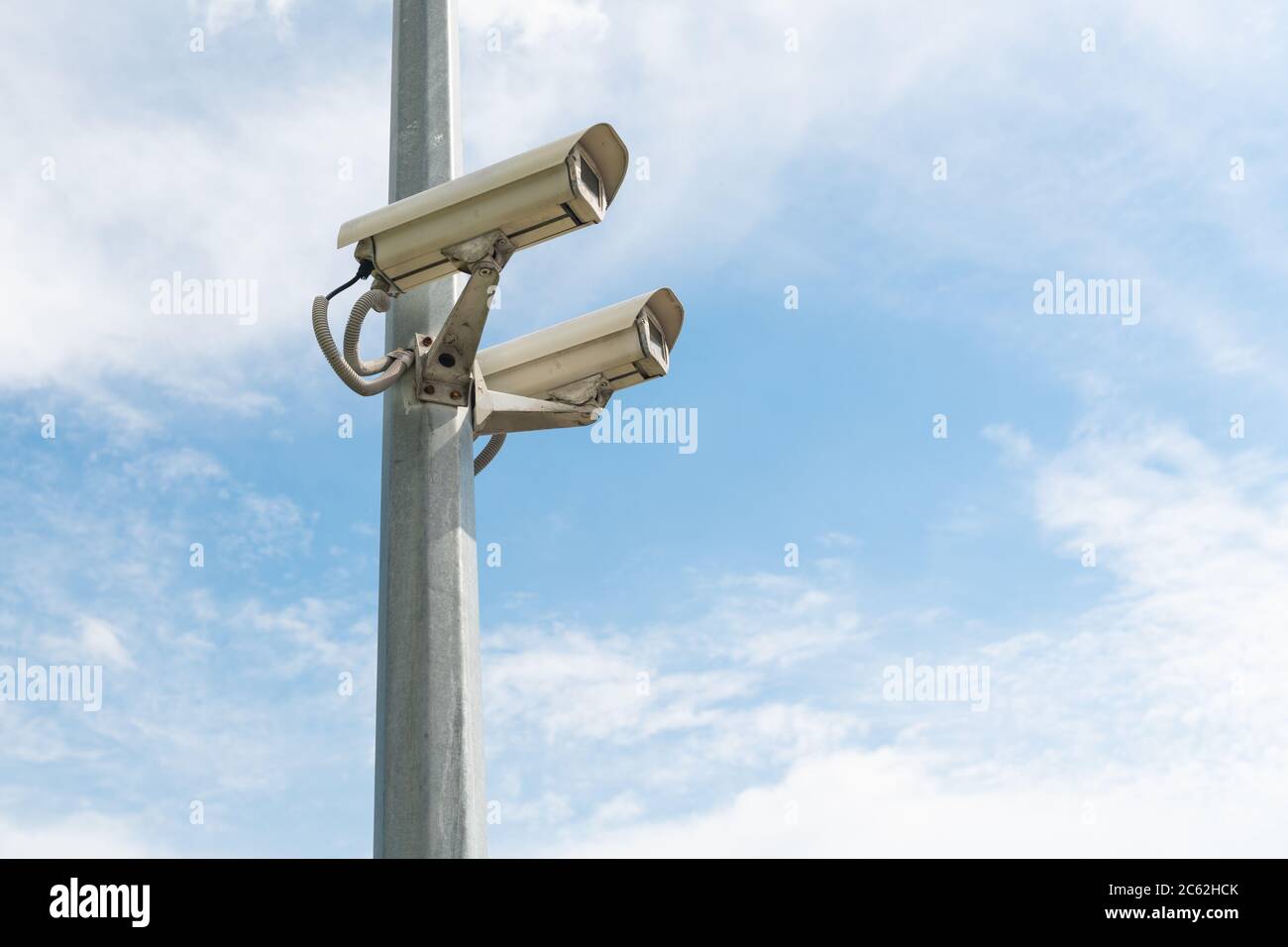 Caméras de sécurité sur un poteau en béton contre le ciel bleu. Photo de haute qualité Banque D'Images